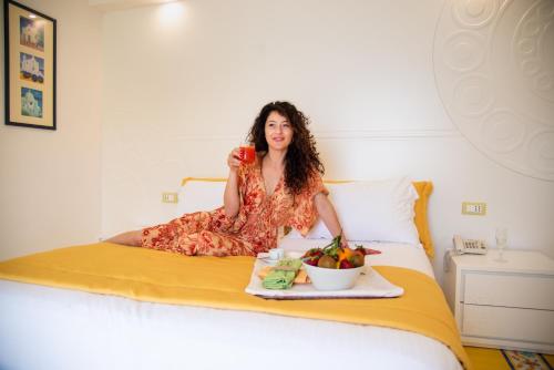 a woman sitting on a bed with a tray of fruit at Hotel Villa Bianca in Ischia