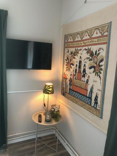 a lamp on a table next to a painting on a wall at Sjugare Gård Bed & Breakfast in Leksand