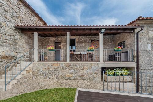 a stone house with a balcony with a table at Private Nature Villa with Saltwater Pool in North Portugal in Cabeceiras de Basto