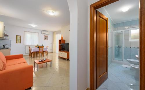 a living room with an orange couch and a bathroom at Villa Franka 113 in Bašanija