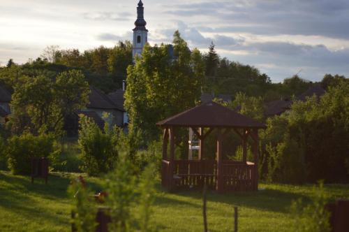a gazebo in a field with a clock tower at Téli Berek Vendégház in Abod