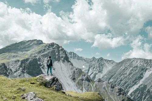 a man standing on top of a mountain at Hotel Alpensonne - Panoramazimmer & Restaurant in Arosa