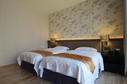 two beds in a hotel room with floral wallpaper at Grand Crystal Hotel in Hsinchu City