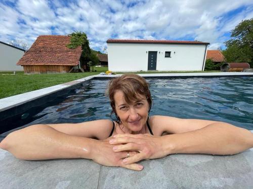 a woman is laying in a swimming pool at Steirerloft in Sankt Peter am Ottersbach