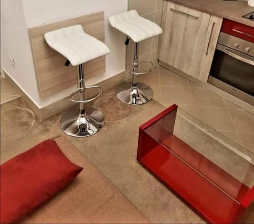 een keuken met 2 barkrukken en een rode tafel bij RoyalWings apartman Jagodina in Jagodina