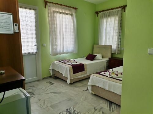 two beds in a room with green walls and windows at Sirius star otel in Ortaca