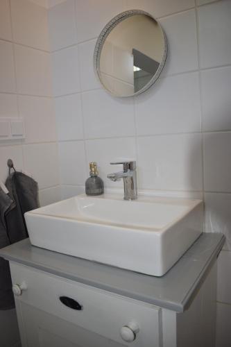 biała umywalka z lustrem na blacie w obiekcie Malomszeg Apartman 2 w mieście Pecz