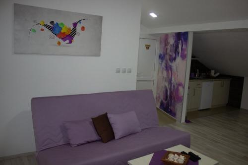 um sofá roxo numa sala de estar com um quadro na parede em Markulev Apartment em Ohrid