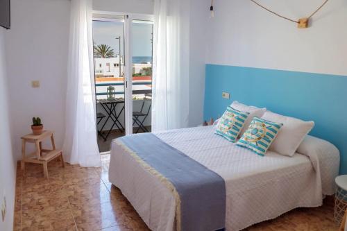 H El Palmeral Playa في موجاكار: غرفة نوم مع سرير كبير مع اللوح الأمامي الأزرق