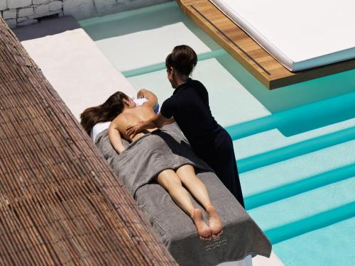 a woman holding a baby on a bed in a swimming pool at Mykonos Earth Suites in Mýkonos City