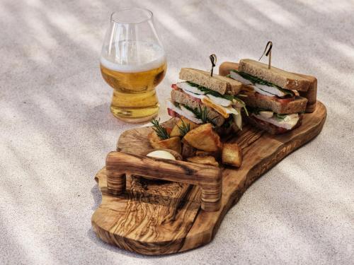 a wooden cutting board with a sandwich and a glass of beer at Mykonos Earth Suites in Mýkonos City