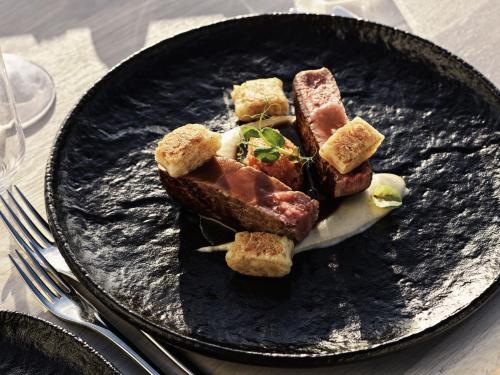 a black plate with food on a table at Mykonos Earth Suites in Mýkonos City