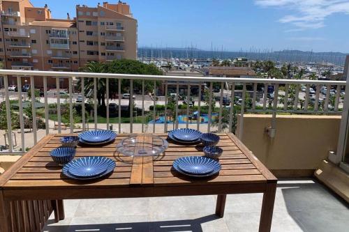 a wooden table with blue bowls on top of a balcony at L'EFFET MER, DUPLEX SUR LE PORT AVEC SES 2 TERRASSES VUE MER in Hyères