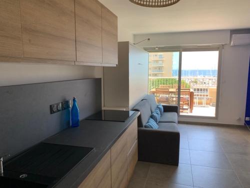 a kitchen and living room with a couch and a table at L'EFFET MER, DUPLEX SUR LE PORT AVEC SES 2 TERRASSES VUE MER in Hyères