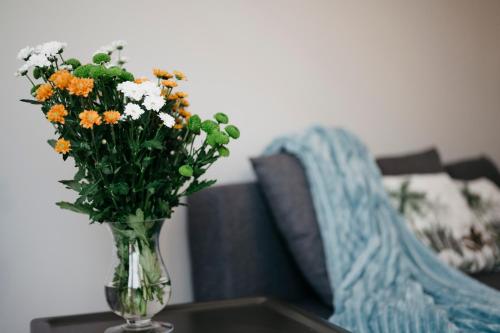 a vase of flowers sitting on a table next to a couch at Nocosfera Apartament Serbinów in Kalisz
