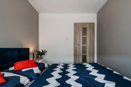 a bedroom with a blue and white bed and a door at Nocosfera Apartament Serbinów in Kalisz