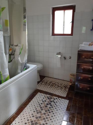 a bathroom with a tub and a toilet and a window at Etno guest house Lalovic in Tjentište