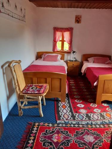 a bedroom with two beds and a chair and a rug at Etno guest house Lalovic in Tjentište