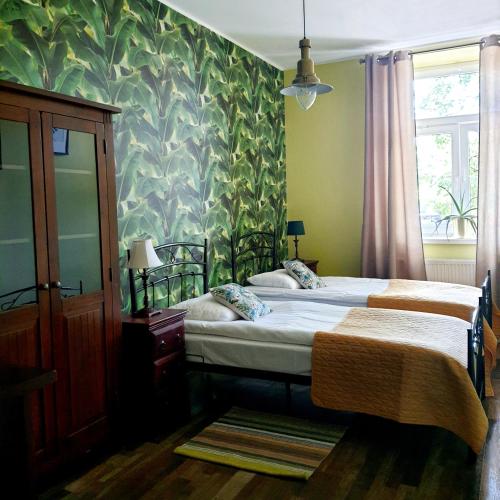 a bedroom with two beds and a green wall at Nowy Rynek 10 in Płock