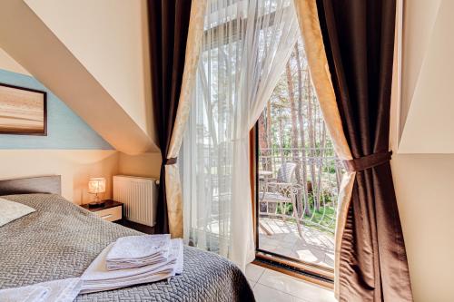 a bedroom with a bed and a large window at Villa Porto in Pobierowo