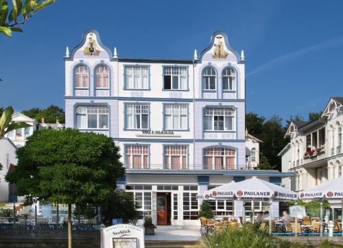 ein großes weißes Gebäude mit einem Restaurant davor in der Unterkunft Hotel Germania in Bansin