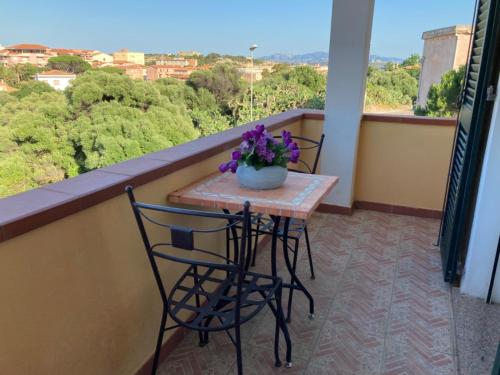 a table with two chairs and a vase of flowers on a balcony at Villa le Bougainvillea in La Maddalena