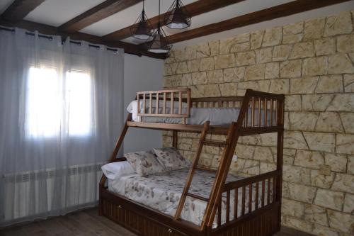 a bedroom with two bunk beds in a stone wall at El Capricho de los Carrascos in Juarros de Voltoya