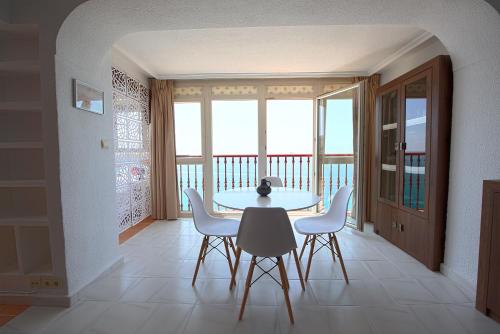 a table and chairs in a room with a balcony at Las Damas Premium 23F Beach Front - Pool & Parking in Benidorm