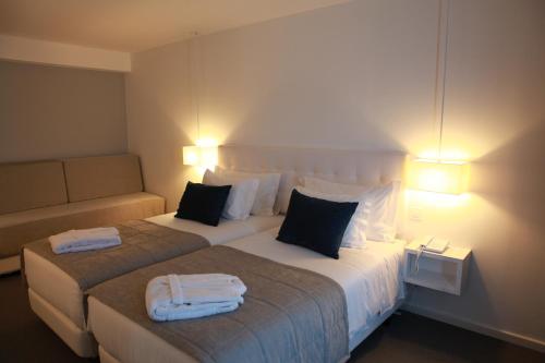 a hotel room with two beds and a couch at Hotel Anjo de Portugal in Fátima