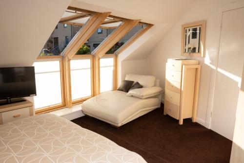 a bedroom with a bed and a tv and some windows at Aberfoyle Inn in Aberfoyle