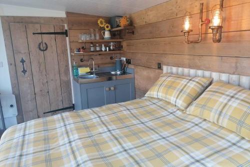 uma cama com um cobertor xadrez num quarto em Crown Cabin Wiltshire near Longleat and Bath em Trowbridge