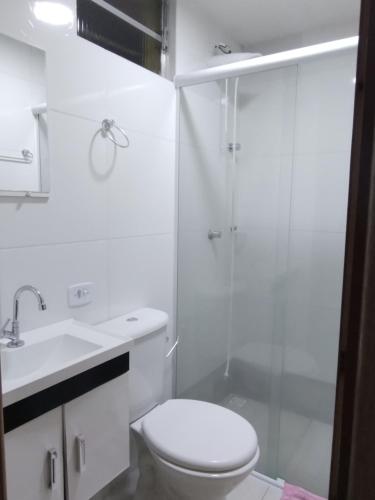 a white bathroom with a toilet and a shower at Suites Bella vista in Campos do Jordão