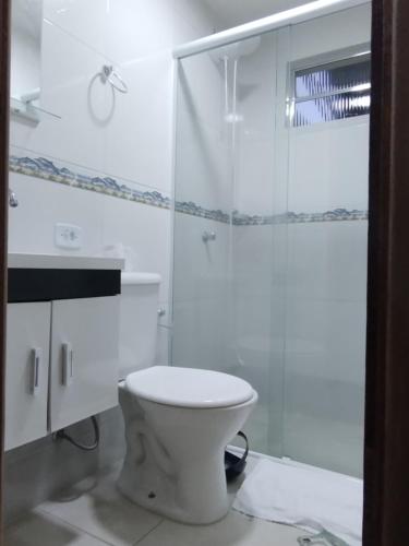 a white bathroom with a toilet and a shower at Suites Bella vista in Campos do Jordão