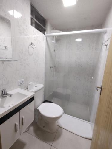 a white bathroom with a toilet and a shower at Suites Bella vista in Campos do Jordão