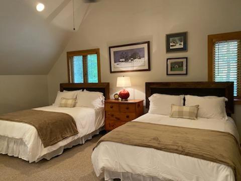 1 dormitorio con 2 camas, mesita de noche y 2 ventanas en Lolly's Treehouse, en Highlands
