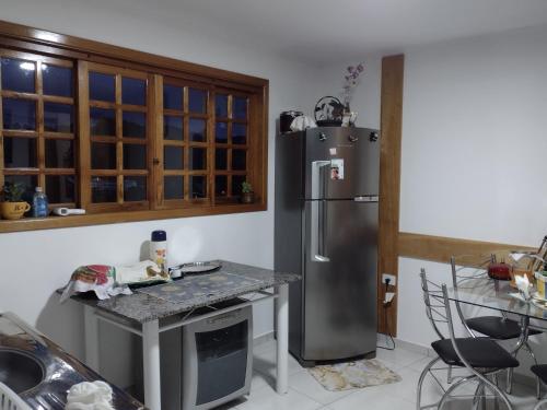 a kitchen with a stainless steel refrigerator and a table at Suites Bella vista in Campos do Jordão