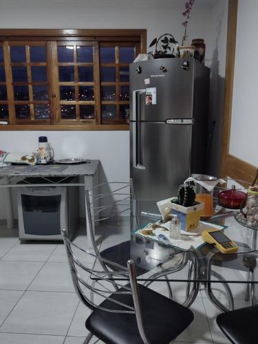 a kitchen with a stainless steel refrigerator and a table at Suites Bella vista in Campos do Jordão