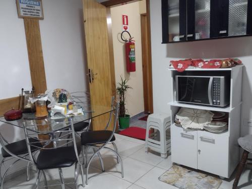 a kitchen with a table and a microwave on a cabinet at Suites Bella vista in Campos do Jordão