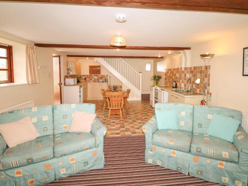 a living room with two couches and a kitchen at The Linney in Northleigh