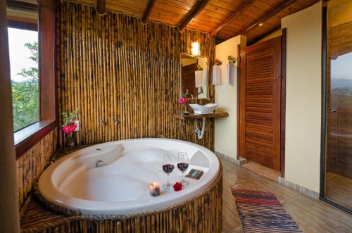 a bathroom with a tub with glasses of wine at Pousada Lua de Minas in Visconde De Maua