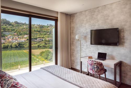 a bedroom with a bed and a desk and a large window at Quinta de Santo António - Country House & Villas in Marco de Canaveses