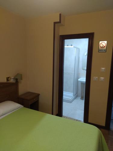 a bedroom with a green bed and a bathroom at Hotel Camagüey in Gijón