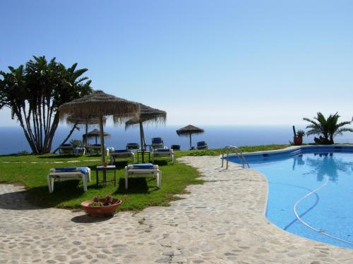 a resort with a swimming pool with chairs and umbrellas at Cortijo La Luna in Almuñécar