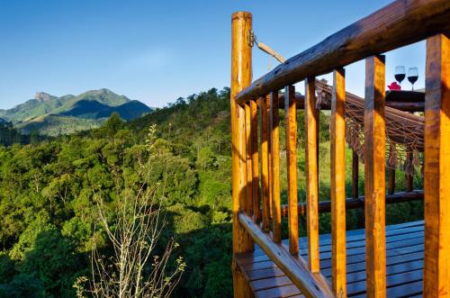 a wooden deck with mountains in the background at Pousada Lua de Minas in Visconde De Maua