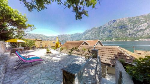 a patio with a chair and an umbrella and water at Dream Catcher Villa - Beachfront & Seaview terrace in Prčanj
