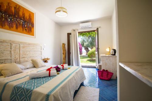 sypialnia z 2 łóżkami i drzwiami do podwórza w obiekcie Suites Voce del Mare w mieście Tertenìa