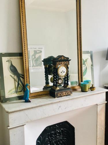 a fireplace mantle with a clock and a mirror at Le Domaine de Villespy in Villespy