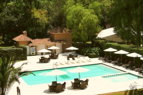 uma vista superior para uma piscina com cadeiras e guarda-sóis em Hotel Real del Bosque Golf and Spa em Tula de Allende