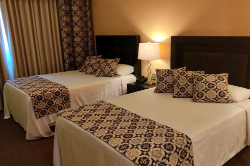 a hotel room with two beds and a lamp at Hotel Real del Bosque Golf and Spa in Tula de Allende