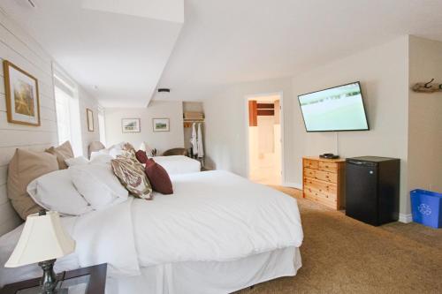 a bedroom with a white bed and a flat screen tv at The Inn at the Ninth Hole Bed & Breakfast in Salmon Arm